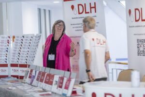 Zwei Helfer aus dem "Infostand-Team" im Gespräch am DLH-Infostand, 29. DLH-Patientenkongress in Bad Wildungen