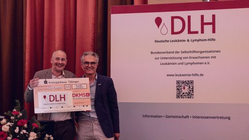 Stephan Schumacher, Geschäftsführer der DKMS Donor Center gGmbH, überreicht Rainer Göbel einen symbolischen Scheck als Geschenk der DKMS zum 30-jährigen DLH-Jubiläum